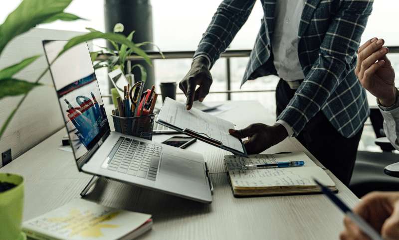 Ilustrasi seorang pemilik usaha sedang memantau grafik penjualan dan menyusun strategi manajemen bisnis di depan laptop.